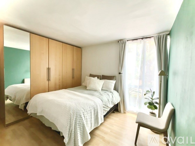 A bedroom with a large bed and a chair.