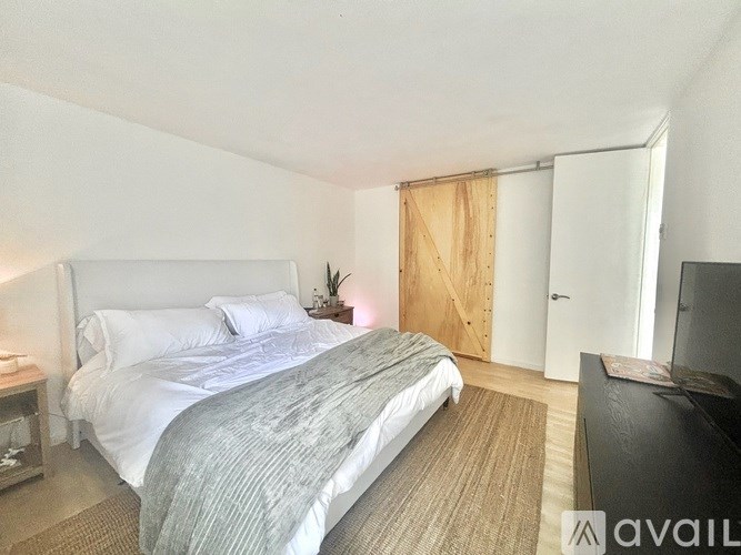 A bedroom with a large bed and a wooden door.