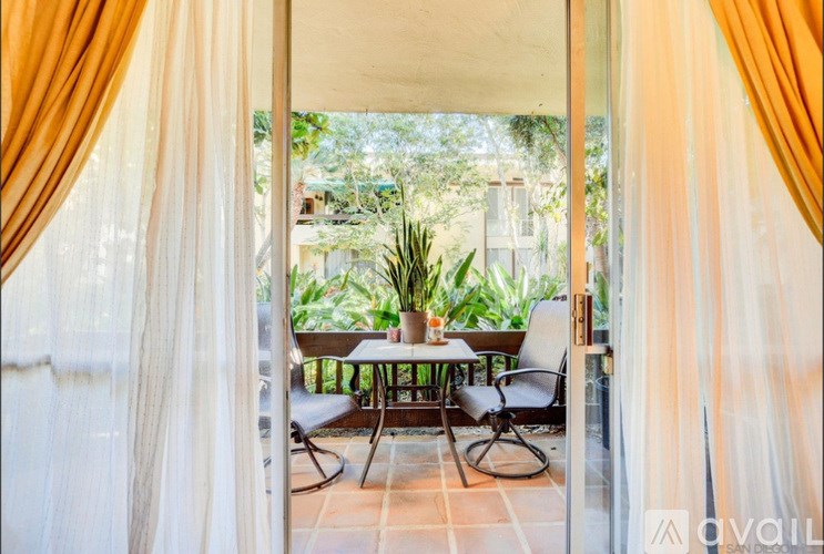 A patio with a table and chairs is visible through a curtain.