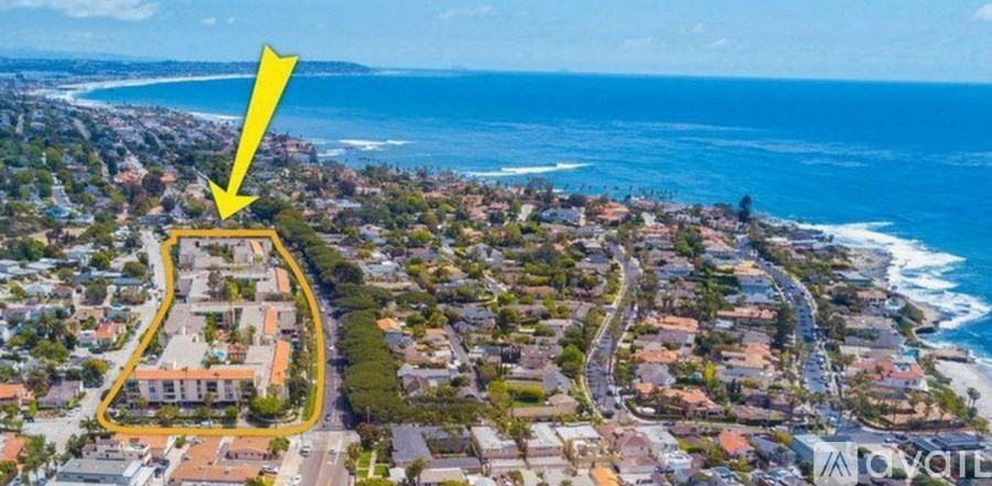 An aerial view of a coastal area with a yellow arrow pointing to a specific property.