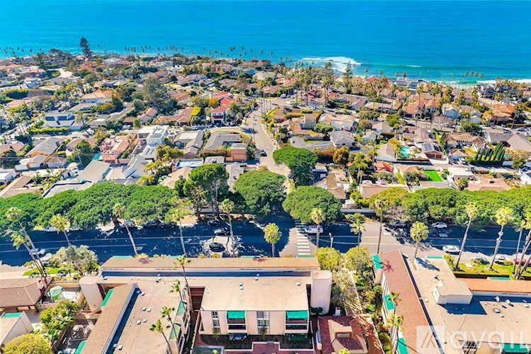 A coastal residential area with houses and a beach in the distance.