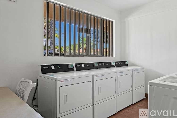 A row of washing machines are in a laundry room.