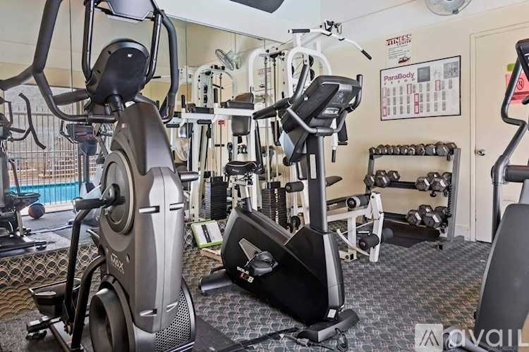 A gym with a variety of exercise equipment including treadmills, stationary bikes, and weight machines.