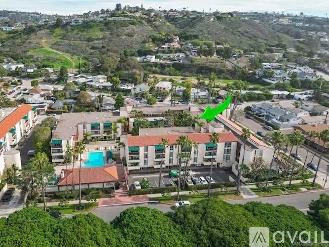 An aerial view of a resort with a swimming pool and a green arrow pointing to a building.