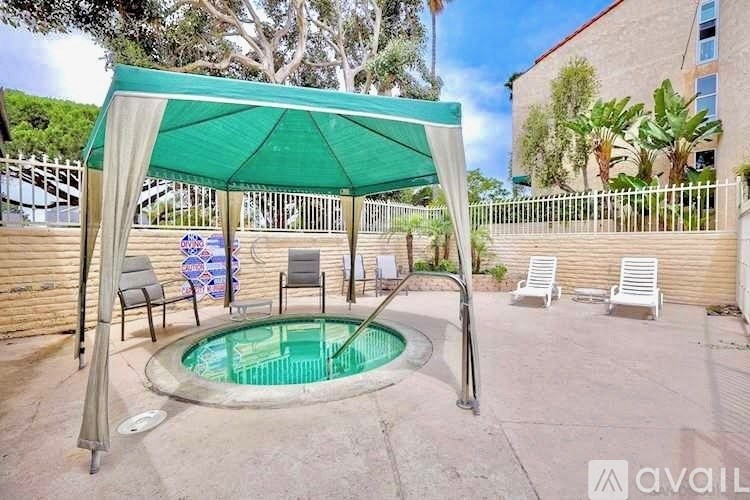 A pool area with a green canopy and white chairs.