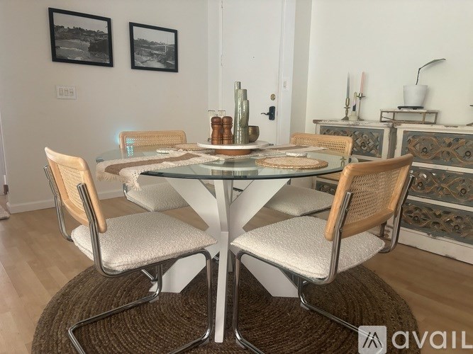 A dining table with four chairs and a rug in the middle of the room.