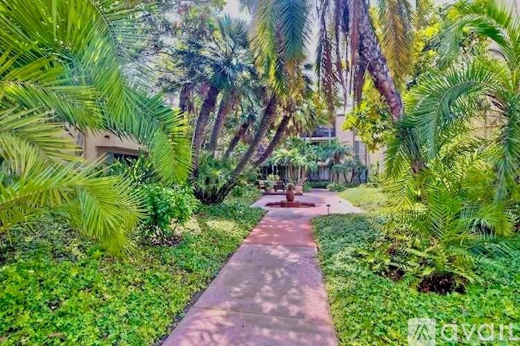 A pathway surrounded by lush greenery and palm trees.