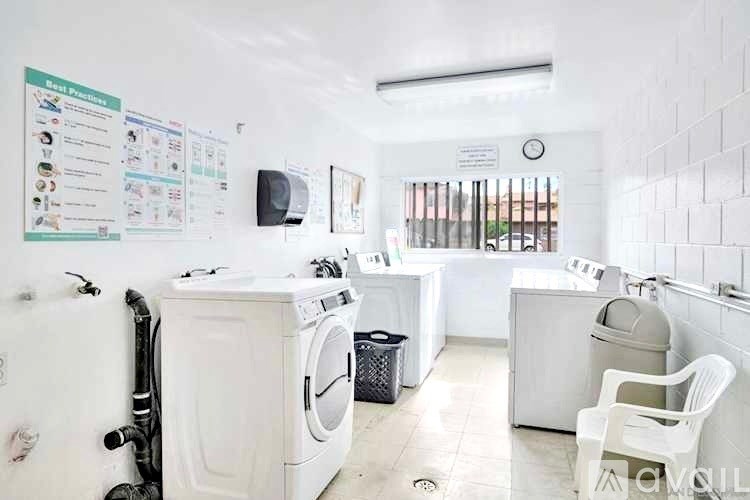 A laundry room with a washer and dryer, a white chair, and a white wall with a poster.