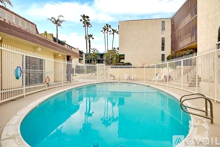 A pool surrounded by a fence with palm trees in the background.