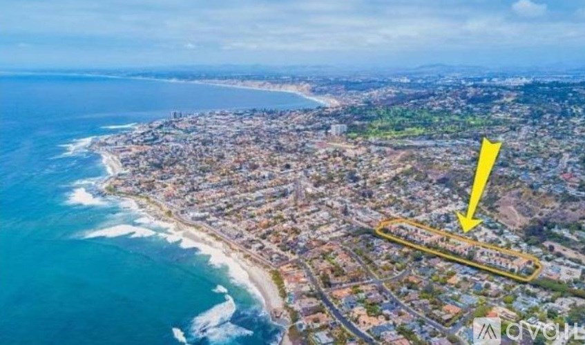 An aerial view of a coastal city with a yellow arrow pointing to a specific area.