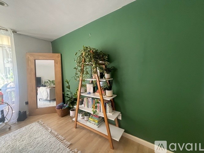 A room with a green wall and a wooden ladder bookshelf.