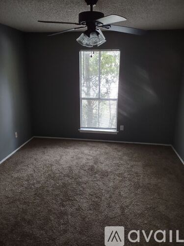 A room with a carpeted floor and a ceiling fan.