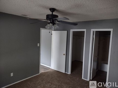 A room with a ceiling fan and three doors.