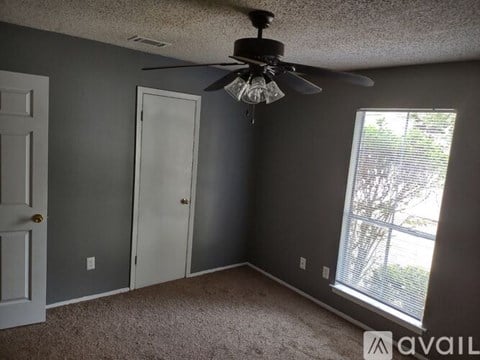 A room with a ceiling fan and a window with blinds.