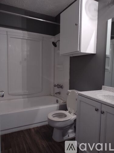 A white toilet in a bathroom with wooden floors and white cabinets.