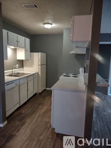 A kitchen with white appliances and wooden floors.