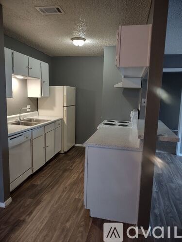 A kitchen with white appliances and wooden floors.