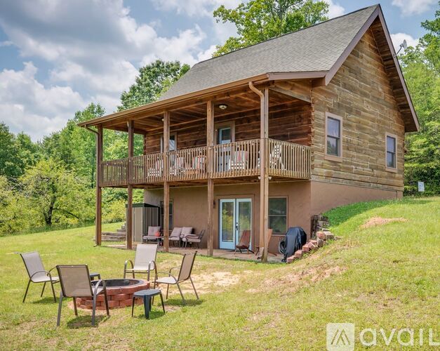 A wooden cabin with a porch and a fire pit in front.