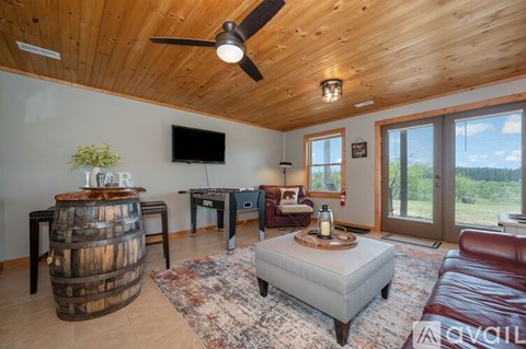 A living room with a wooden ceiling and a flat screen TV mounted on the wall.