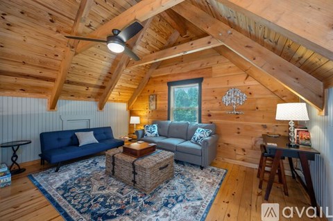 A cozy living room with a blue couch and a wooden ceiling.
