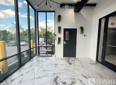 A room with a black door and a glass wall with a view of the street.