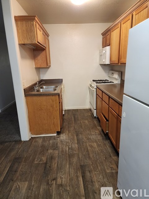 A kitchen with a white refrigerator, wooden cabinets, and a white stove top oven.