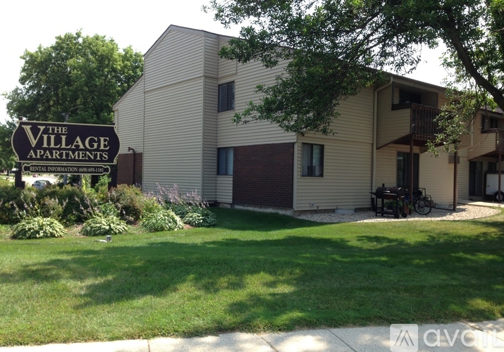 A sign that says "The Village Apartments" is in front of a building.