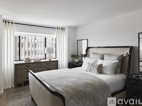 A bedroom with a large bed, a nightstand, and a window with curtains.