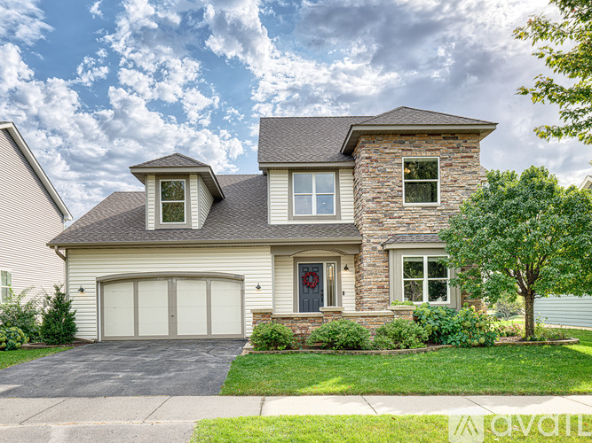 A two-story house with a garage and a tree in front.