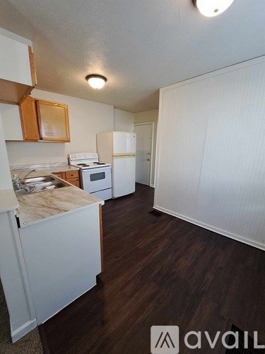 A kitchen with white cabinets and a white fridge.