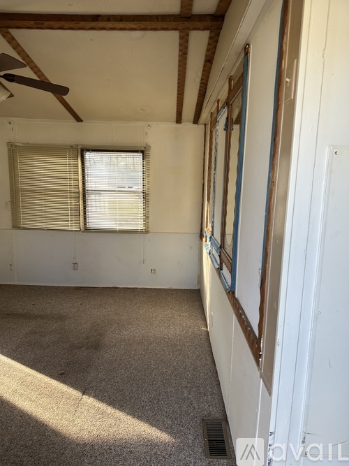 A room with a ceiling fan and a window with blinds.