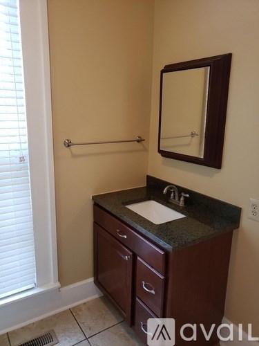 A bathroom with a sink, mirror, and a window.