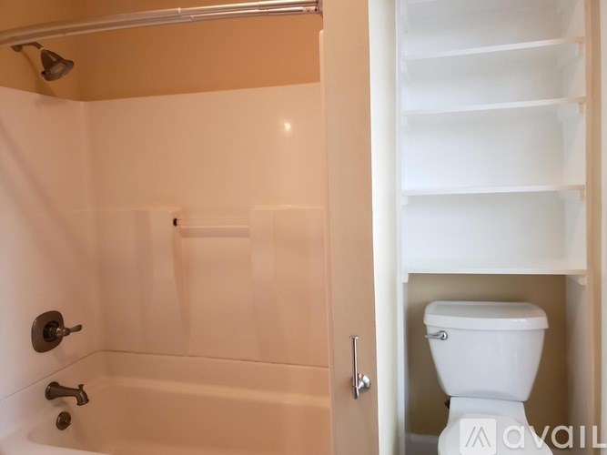 A white toilet is in a bathroom with a white bathtub.