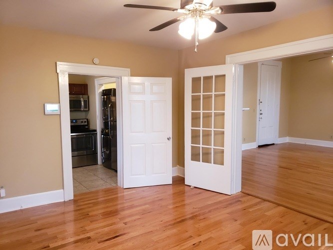 A room with a ceiling fan and wooden flooring.