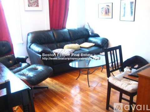 A living room with a black leather couch and a glass table.