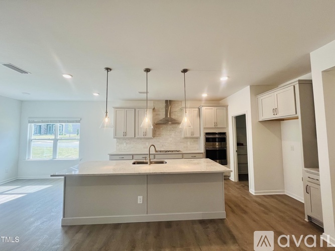 A modern kitchen with a large island and pendant lights.