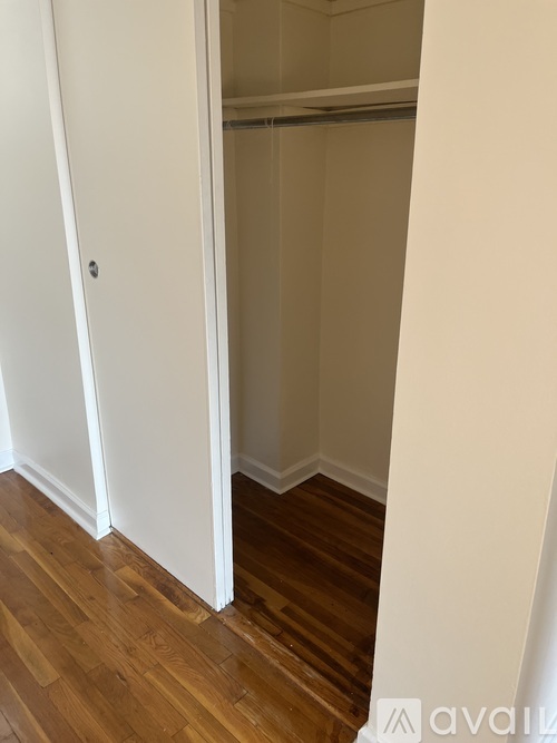 A room with a white door and wooden floor.