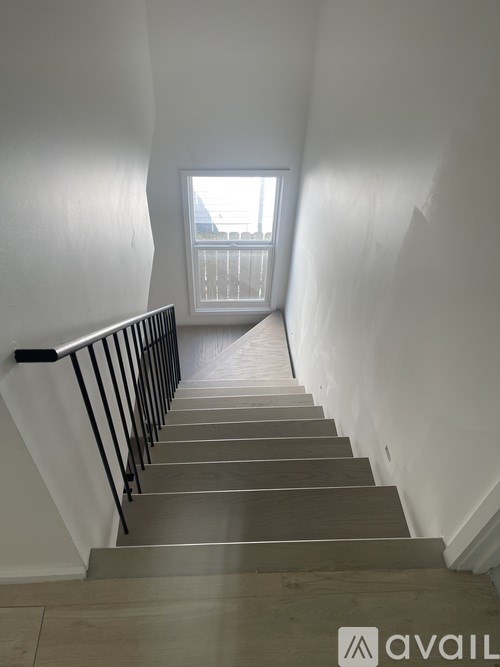A staircase with a metal railing and wooden steps leading to a window.