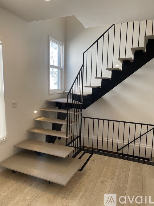 A black metal staircase with a wooden handrail and steps.
