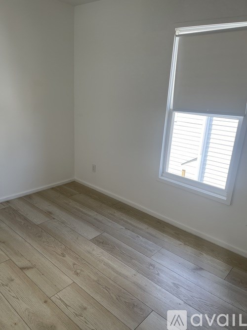 A room with wooden flooring and a window with blinds.