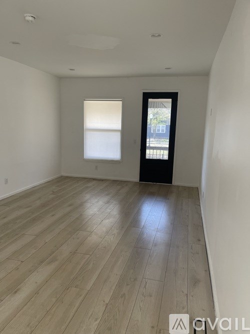 A room with wooden flooring and a door leading outside.