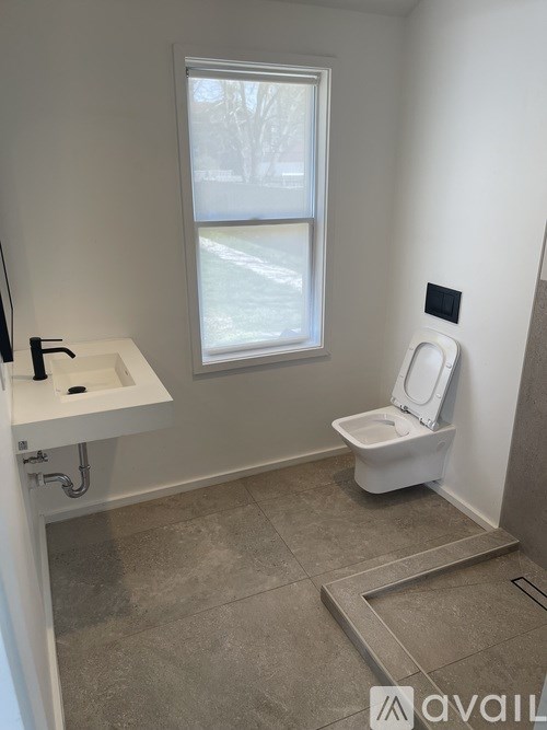 A bathroom with a toilet, sink, and window.