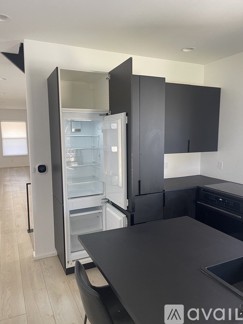 A kitchen with a black countertop and a refrigerator with the door open.