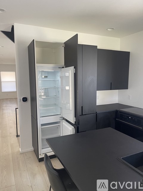 A kitchen with a black countertop and a refrigerator with the door open.