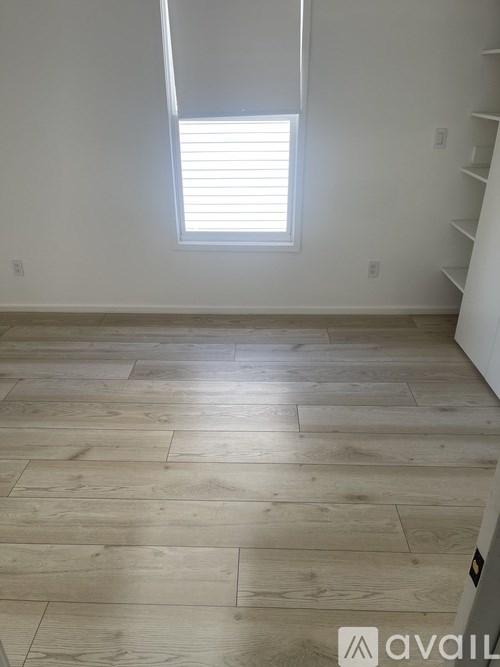 A room with wooden flooring and a window with blinds.