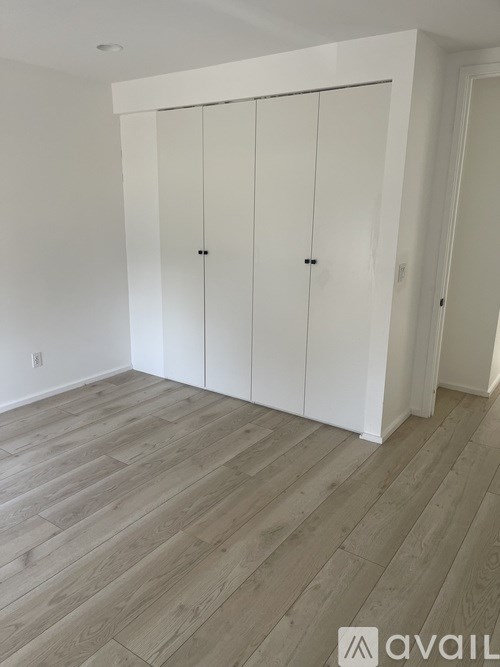 A room with a white cabinet and wooden flooring.