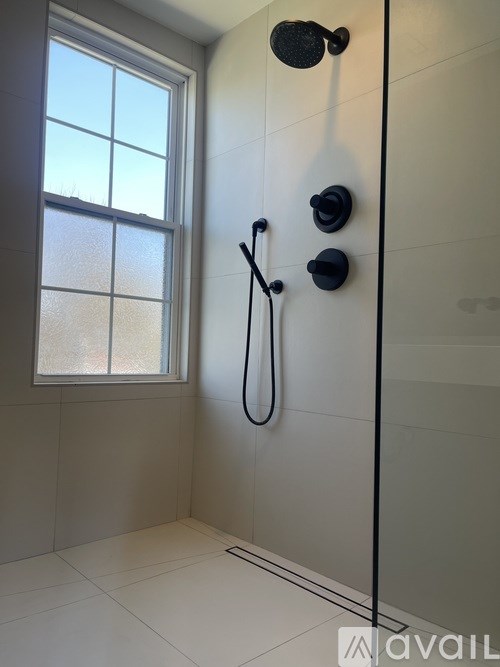 A shower area with a glass door and a window.