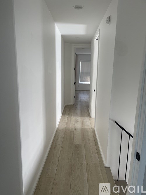 A long hallway with wood floors and white walls.