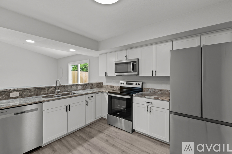 A modern kitchen with white cabinets and stainless steel appliances.