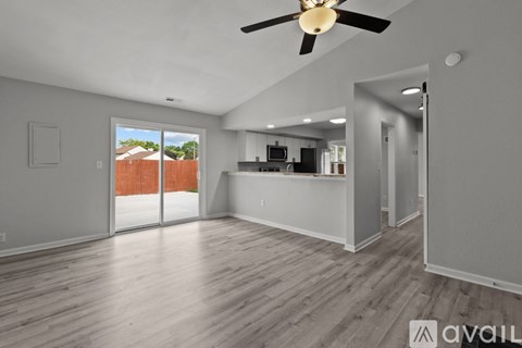 A spacious room with a ceiling fan and sliding glass doors.